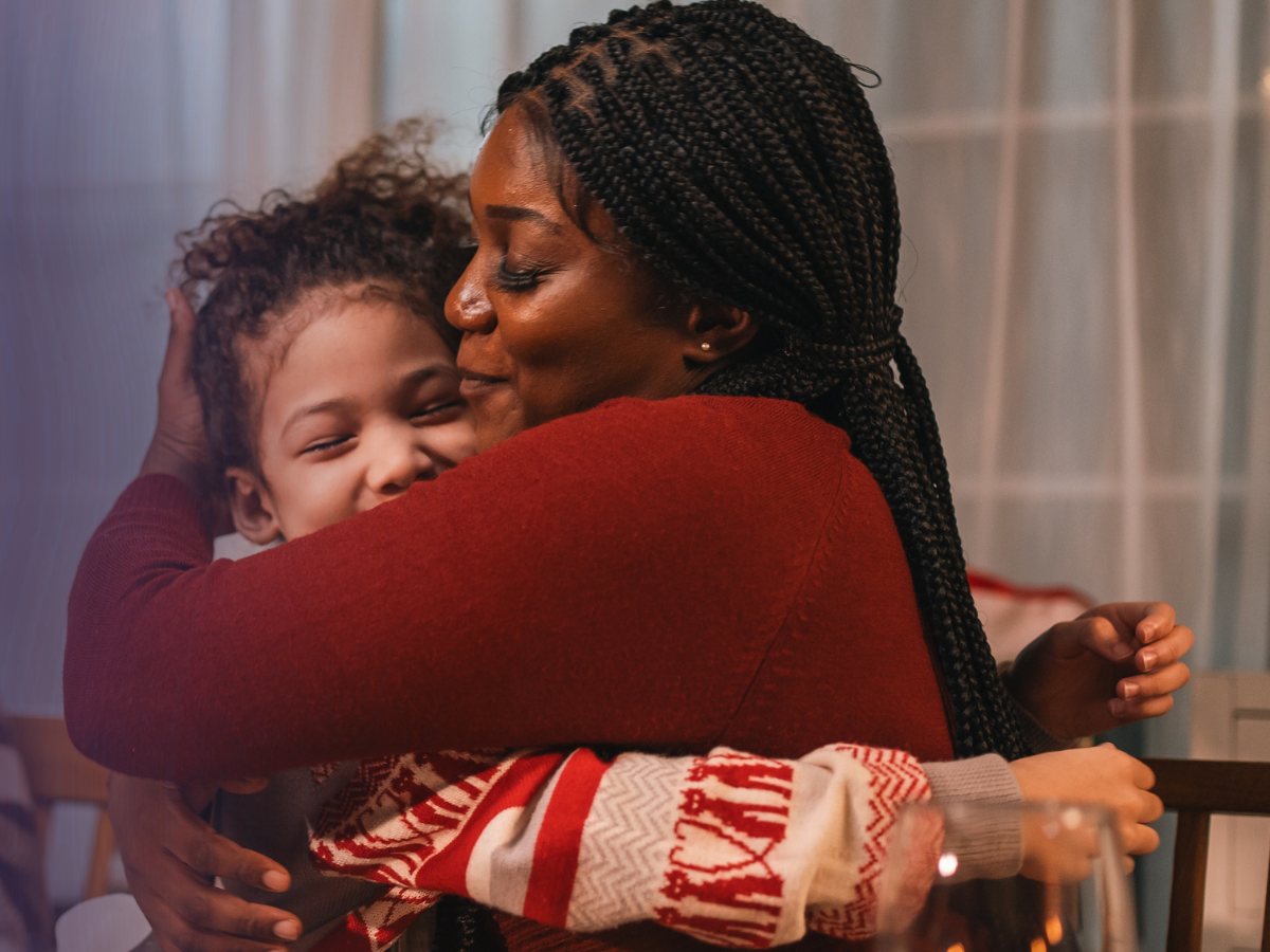 A mother embracing her daughter warmly, both smiling.