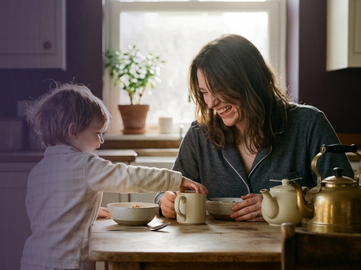 A mother and toddler sharing breakfast at a warm kitchen table.