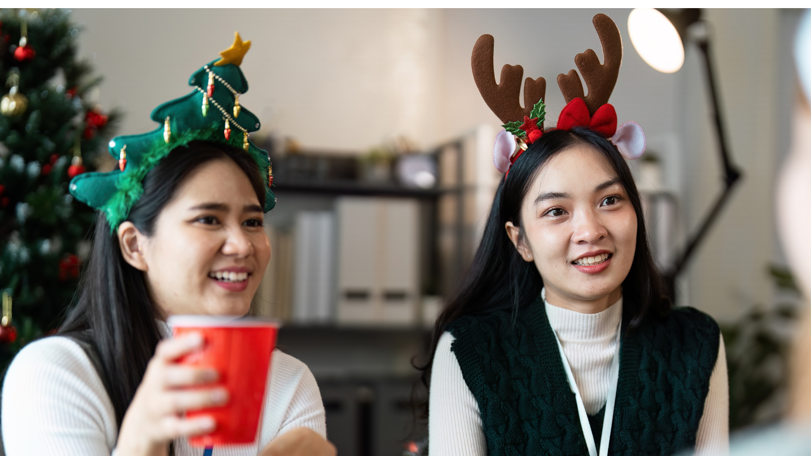 Two women laughing together at a holiday gathering.