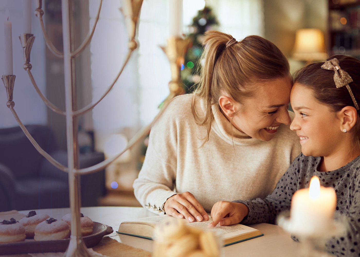 A mother and her young son sharing a warm conversation at a candlelit holiday table.
